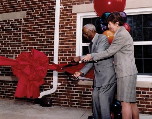 John Hope Franklin and a woman cutting a red ribbon at the opening ceremony for the John Hope Franklin Center